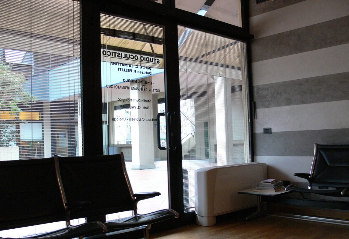 Sala d'attesa dello Studio Oculistico Postorino-La Mattina a La Spezia, vista verso l'ingresso e le insegne dei medici
